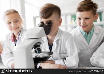 education, science and children concept - kids or students with microscope studying biology at school laboratory. kids or students with microscope biology at school. kids or students with microscope biology at school