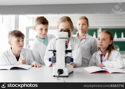 education, science and children concept - kids or students with microscope studying biology at school laboratory. kids or students with microscope biology at school