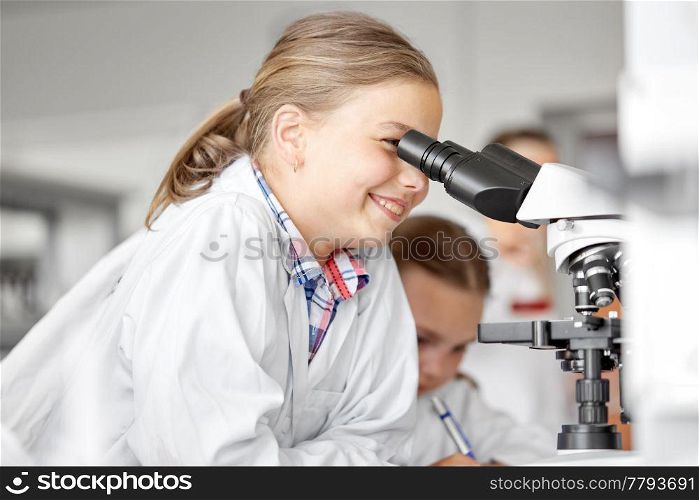 education, science and children concept - kids or students with microscope studying biology at school laboratory. kids or students with microscope biology at school