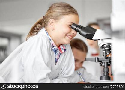 education, science and children concept - kids or students with microscope studying biology at school laboratory. kids or students with microscope biology at school