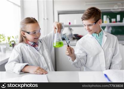 education, science and children concept - kids or students with test tube and magnifier studying chemistry at school laboratory. kids with flask and magnifier at chemistry class