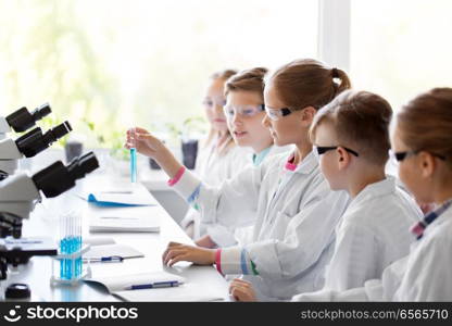 education, science and children concept - kids with test tubes studying chemistry at school laboratory. kids with test tubes studying chemistry at school