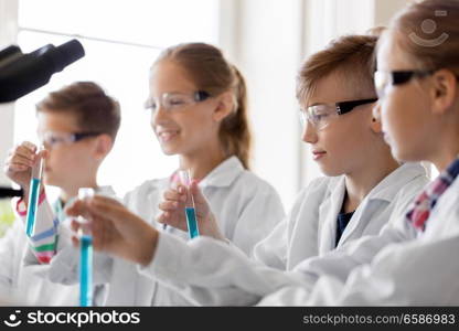 education, science and children concept - kids with test tubes studying chemistry at school laboratory. kids with test tubes studying chemistry at school