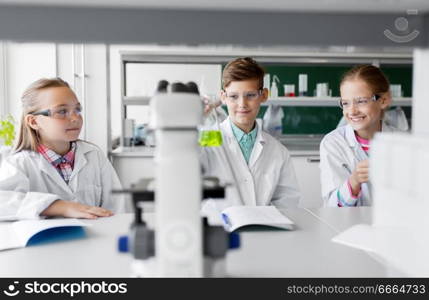 education, science and children concept - kids with test tubes studying chemistry at school laboratory. kids with test tubes studying chemistry at school