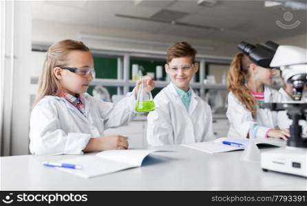education, science and children concept - kids with test tubes studying chemistry at school laboratory. kids with test tubes studying chemistry at school