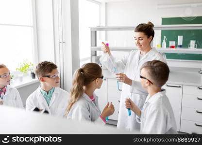 education, science and children concept - teacher and kids or students with test tubes studying chemistry at school laboratory. teacher and students studying chemistry at school. teacher and students studying chemistry at school
