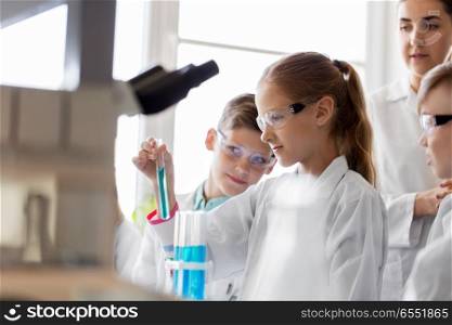 education, science and children concept - teacher and students with test tubes studying chemistry at school laboratory. teacher and students studying chemistry at school. teacher and students studying chemistry at school
