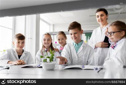 education, science and school concept - kids or students and teacher with plant at biology class. students and teacher with plant at biology class. students and teacher with plant at biology class