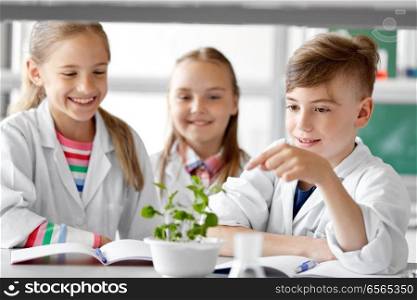 education, science and school concept - kids or students with plant at biology class. kids or students with plant at biology class