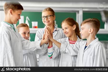 education, science and success concept - happy kids at school laboratory and making high five. happy kids making high five at school laboratory