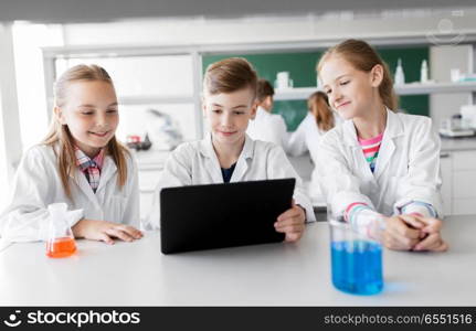 education, science and technology concept - kids with tablet pc computer studying chemistry at school laboratory. kids with tablet pc at school laboratory. kids with tablet pc at school laboratory