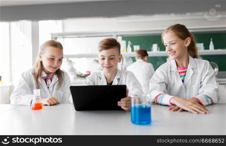 education, science and technology concept - kids with tablet pc computer studying chemistry at school laboratory. kids with tablet pc at school laboratory. kids with tablet pc at school laboratory