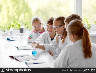 education, science, chemistry and children concept - kids or students with test tube making experiment at school laboratory. kids with test tube studying chemistry at school