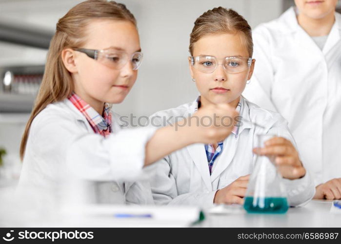 education, science, chemistry and children concept - kids or students with test tube making experiment at school laboratory. kids with test tube studying chemistry at school