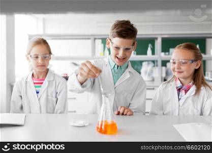 education, science, chemistry and children concept - kids or students with test tube making experiment at school laboratory. kids with test tube studying chemistry at school