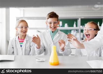 education, science, chemistry and children concept - kids or students with test tube making experiment at school laboratory. kids with test tube studying chemistry at school. kids with test tube studying chemistry at school