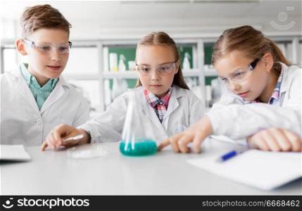 education, science, chemistry and children concept - kids or students with test tube making experiment at school laboratory. kids with test tube studying chemistry at school. kids with test tube studying chemistry at school