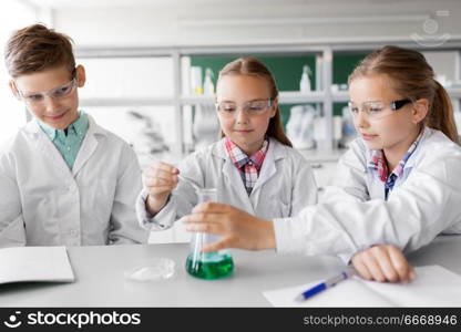 education, science, chemistry and children concept - kids or students with test tube making experiment at school laboratory. kids with test tube studying chemistry at school. kids with test tube studying chemistry at school