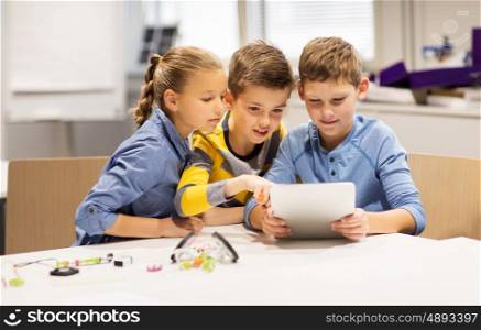 education, science, technology, children and people concept - group of happy kids or students with tablet pc computer programming electric toys and building robots at robotics school lesson