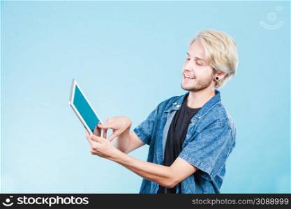 Education social media. Modern technology internet concept. Stylish handsome young guy using tablet computer, on blue color. Trendy young guy using tablet computer