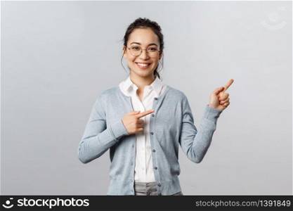 Education, studying and online classes concept. Cheerful asian woman, teacher pointing fingers right at presentation or chart, smiling friendly, helping find way, showing promo, grey background.. Education, studying and online classes concept. Cheerful asian woman, teacher pointing fingers right at presentation or chart, smiling friendly, helping find way, showing promo, grey background