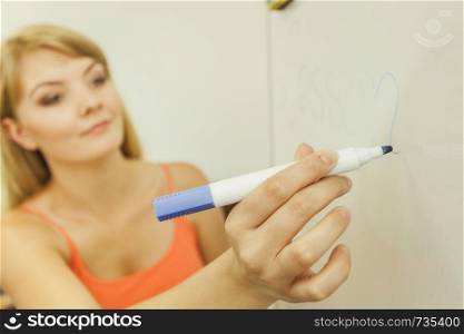 Education, teaching and learning concept - Young woman with marker writing word lesson on whiteboard. woman with marker writing word lesson on whiteboard