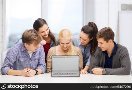 education, technology, advertisement and internet concept - group of smiling students looking at blank black laptop screen