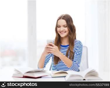 education, technology and home concept - happy smiling student girl with smartphone and books