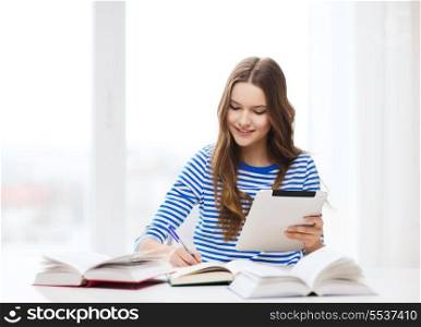 education, technology and home concept - happy smiling student girl with teablet pc computer and books at home