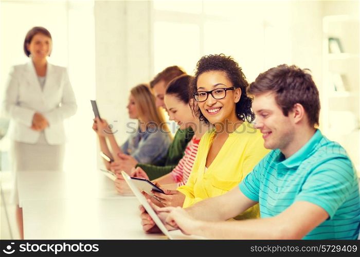education, technology and internet concept - smiling female students with tablet pc computer and friends on the back at school