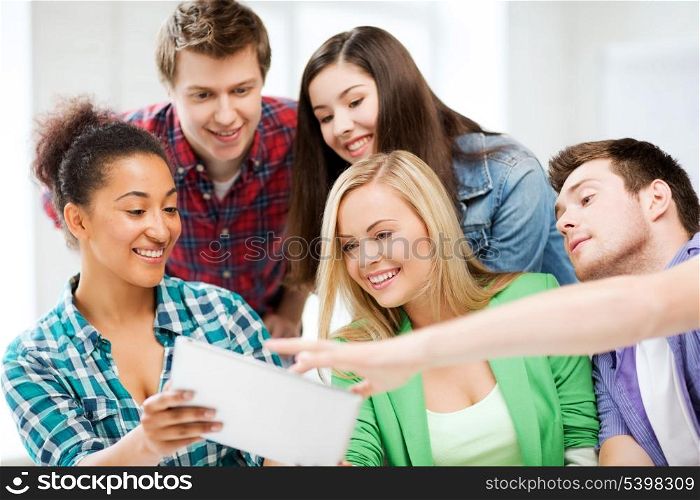 education, technology and internet concept - smiling students looking at tablet pc at school