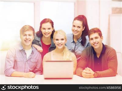 education, technology and internet concept - smiling students with laptop at school