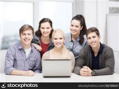 education, technology and internet concept - smiling students with laptop at school
