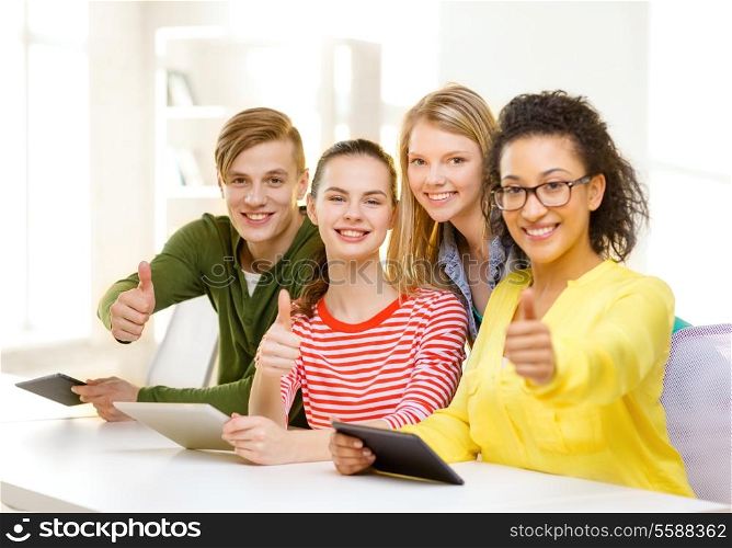 education, technology and internet concept - smiling students with tablet pc computer at school showing thumbs up