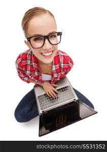 education, technology and internet concept - smiling teenage girl in black eyeglasses with laptop computer