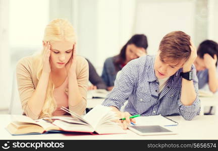 education, technology and internet concept - tired students with tablet pc, books and notebooks preparing for exam