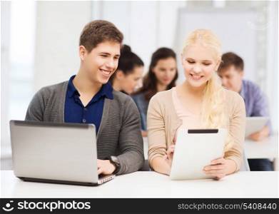 education, technology and internet concept - two smiling girl students with laptop and tablet pc at school