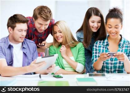 education, technology and internet - students looking at smartphones and tablet pc