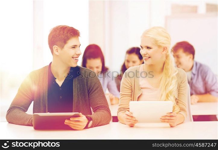 education, technology and internet - two smiling students looking at tablet pc in lecture at school