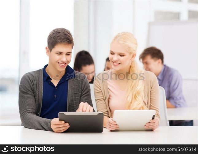 education, technology and internet - two smiling students looking at tablet pc in lecture at school