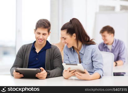 education, technology and internet - two smiling students looking at tablet pc in lecture at school