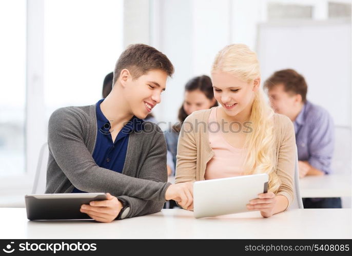 education, technology and internet - two smiling students looking at tablet pc in lecture at school