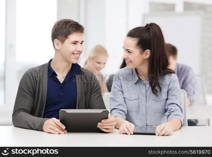 education, technology and internet - two smiling students looking at tablet pc in lecture at school