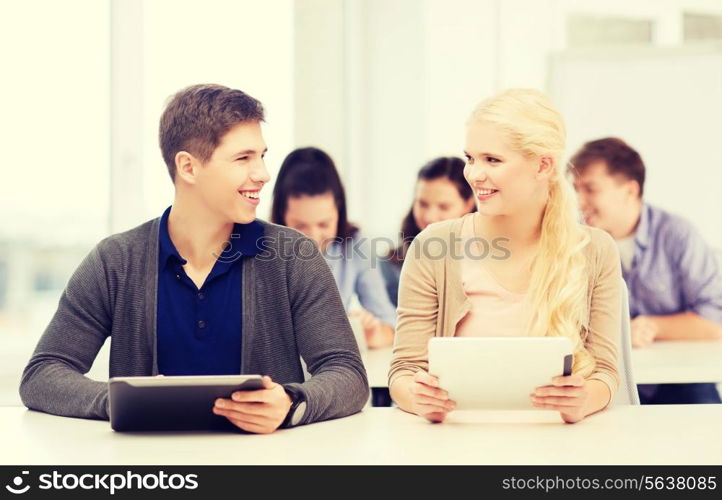 education, technology and internet - two smiling students looking at tablet pc in lecture at school