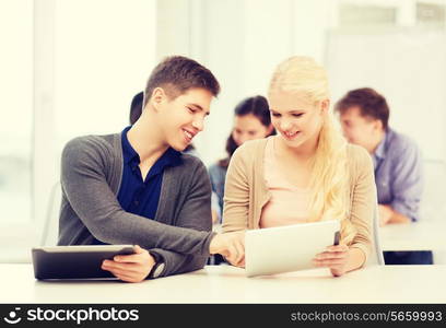 education, technology and internet - two smiling students looking at tablet pc in lecture at school