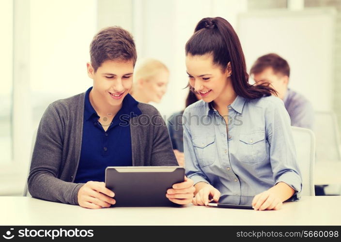 education, technology and internet - two smiling students looking at tablet pc in lecture at school