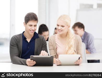 education, technology and internet - two smiling students looking at tablet pc in lecture at school