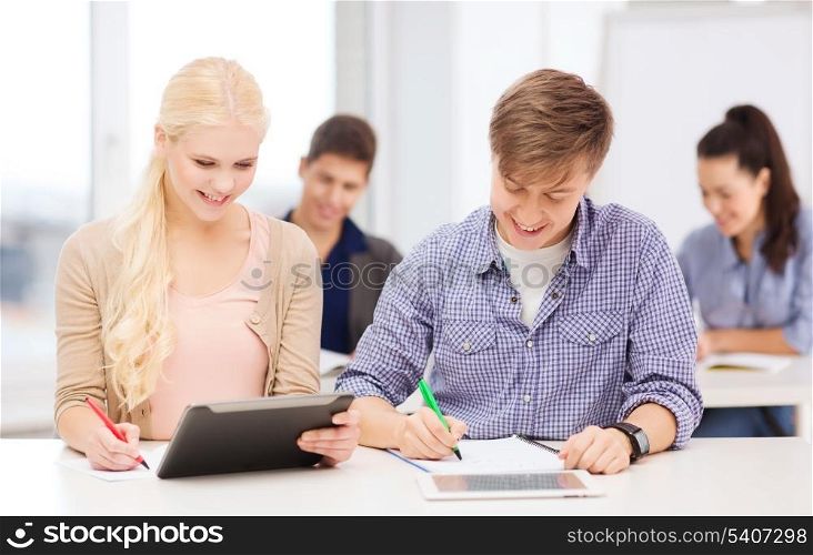 education, technology and internet - two smiling students with tablet pc and notebooks