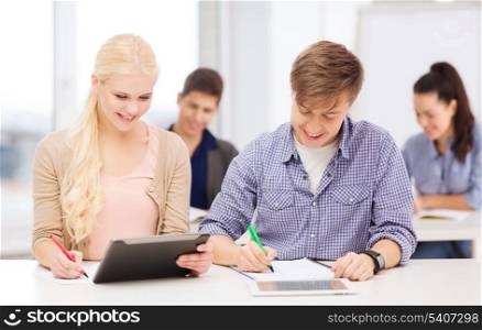 education, technology and internet - two smiling students with tablet pc and notebooks
