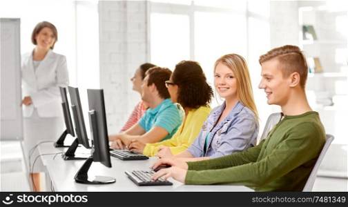 education, technology and learning concept - group of happy international high school students or classmates in computer class. happy high school students in computer class